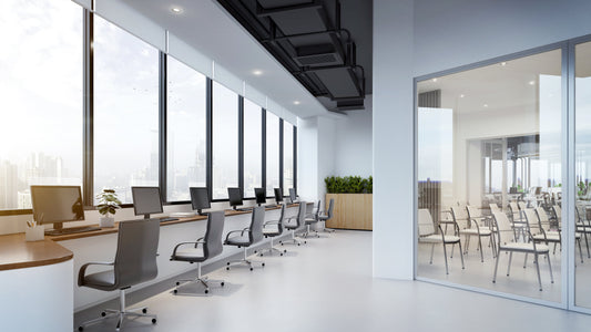 Modern office interior with large glass windows illuminated by recessed LED commercial downlights providing clean, efficient overhead lighting