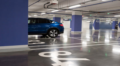 LED Vapor Tight Fixtures providing bright and energy-efficient lighting for parking garage spaces, with a blue car illuminated by the fixtures