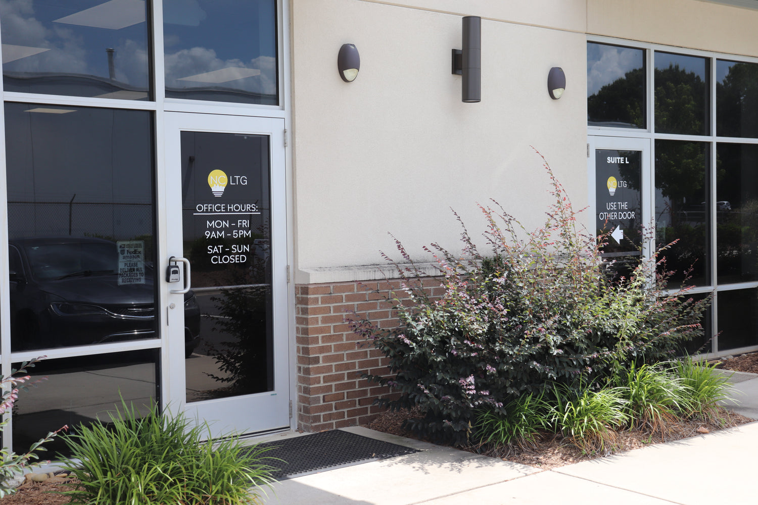 Front entrance of NCLTG’s Charlotte, NC facility showing both the warehouse and office spaces with posted hours of operation.